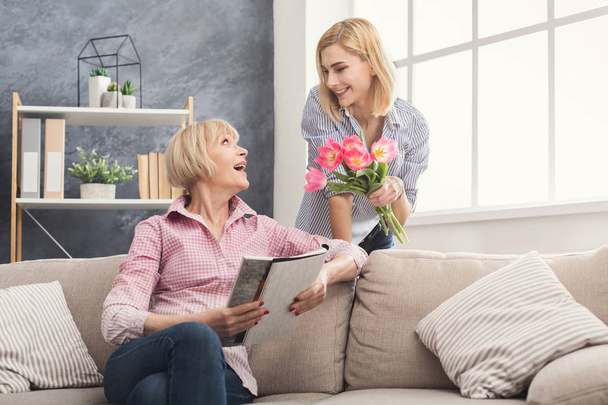 Daughter giving flowers to adult mother - Foto, Imagen