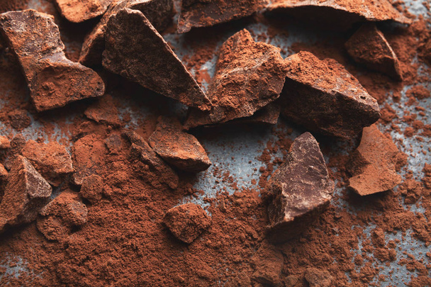 Σπασμένα κομμάτια σοκολάτας και κακάο σε γκρίζο φόντο - Φωτογραφία, εικόνα