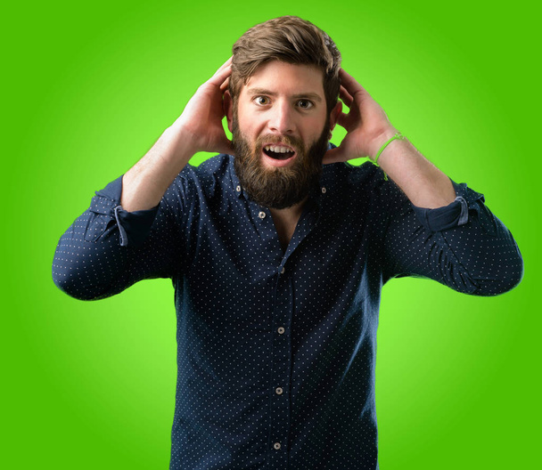 Молодий хіпстер з великою бородою щасливий і здивований веселий, виражаючи жест на зеленому тлі
 - Фото, зображення