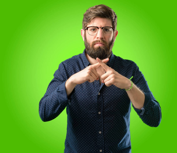 Jeune homme hipster avec une grosse barbe agacé avec une mauvaise attitude faire stop signe avec la main, dire non, exprimer la sécurité, la défense ou la restriction, peut-être pousser sur fond vert
 - Photo, image