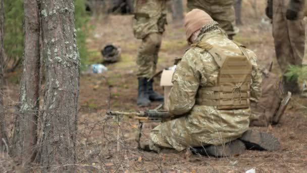 Soldaten in Tarnkleidung bereiten sich auf den Kampf vor und prüfen Ausrüstung und Waffen - Filmmaterial, Video