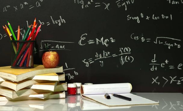 Kirjat on pinottu pöydälle vastaan matemaattisia yhtälöitä blackboard
 - Valokuva, kuva