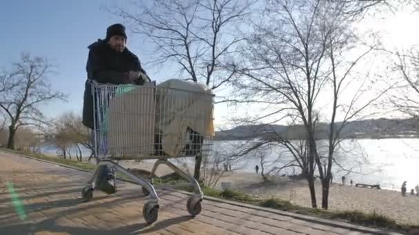 Edessä näkymä koditon kypsä mies työntää ostoskoriin
 - Materiaali, video