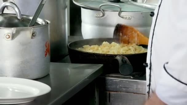 キッチンでフライパンに植物油で揚げた玉ねぎのみじん切り - 映像、動画