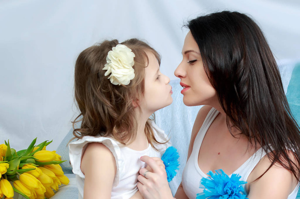 Mom and daughter on the sofa with a bouquet of flowers. - Photo, Image