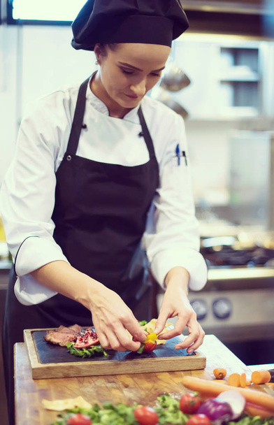 female Chef in restaurant kitchen preparing beef steak with vegetable decoration - Valokuva, kuva