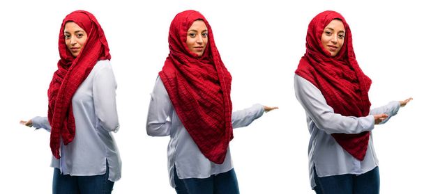 Mujer árabe usando hijab confiado y feliz con una gran sonrisa natural invitando a entrar aislado sobre fondo blanco
 - Foto, imagen