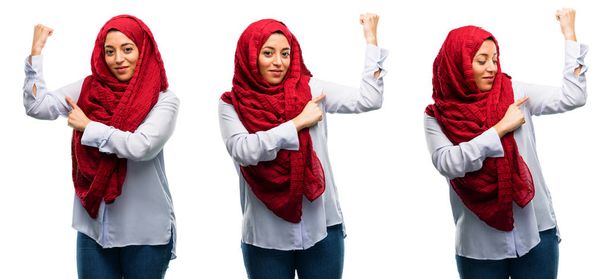Mujer árabe usando hijab apuntando bíceps expresando la fuerza y el concepto de gimnasio, la vida sana su buen aislado sobre fondo blanco
 - Foto, imagen