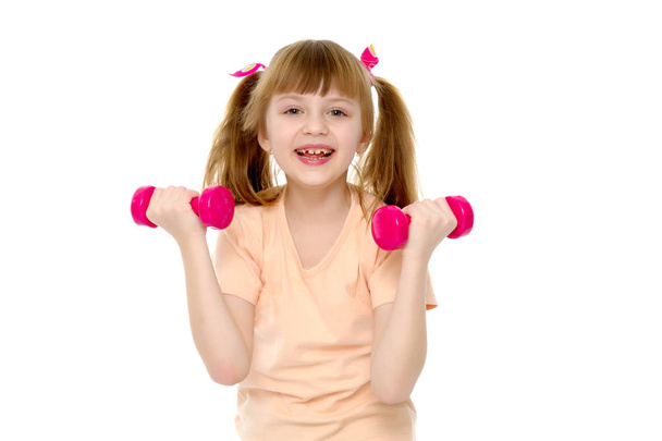 Little girl doing exercises with dumbbells. - Fotografie, Obrázek