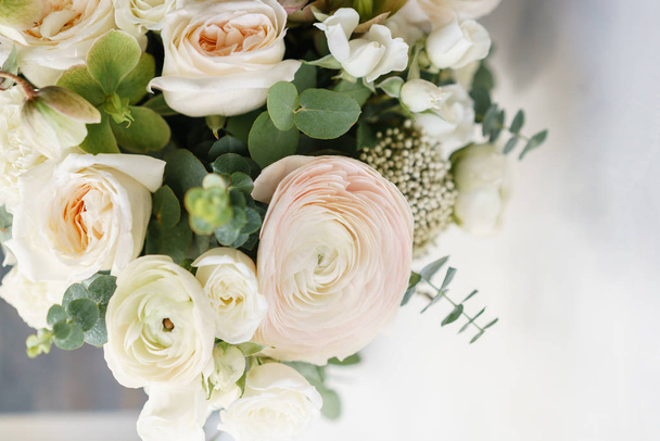 Beyaz güller sevdiceğim ahşap bir masa üzerinde bir buket düğün. Bir sürü yeşillik, asimetrik modern gelin grup darmadağınık. - Fotoğraf, Görsel