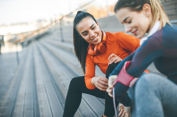 Twee jonge aantrekkelijke vrouwelijke atleet nemen pauze na het joggen buiten - Foto, afbeelding