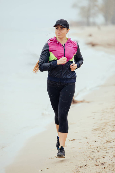 Woman jogging on river beach at the rainy day - Foto, immagini