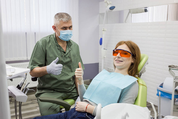Woman and dentist showing thumb up sign at office (clinic) - Foto, Imagen