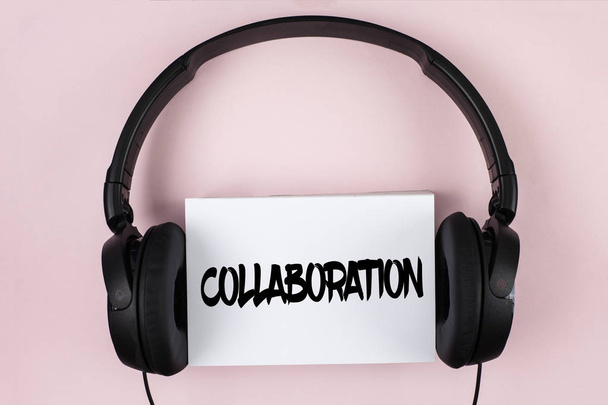 Handwriting text Collaboration. Concept meaning Global industries partnership with teamwork to help others win written on White Sticky Note paper on plain Pink background Headphone next to it. - Photo, Image