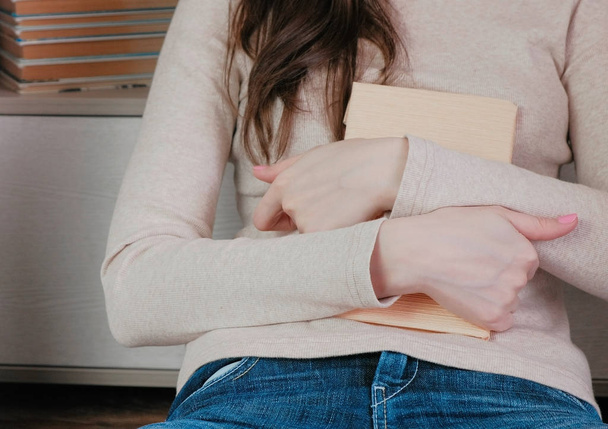 Close-up of the womans hands hugging the book. - Foto, afbeelding