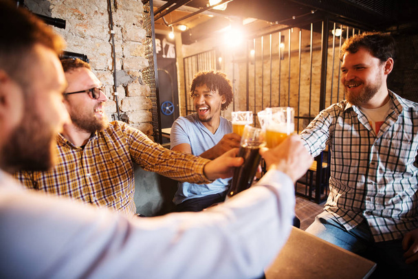 jeunes hommes barbus heureux célébrant et griller avec de la bière dans le pub
 - Photo, image