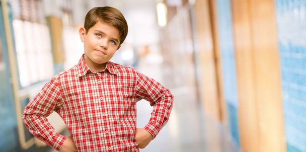 Niño guapo con ojos verdes confiado y feliz con una gran sonrisa natural riendo en el pasillo de la escuela
 - Foto, imagen