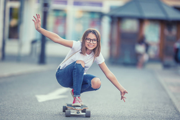 Cut young skater girl riding on her longboard in the city - Foto, imagen