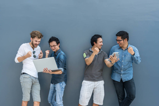 Ryhmä Aasian ja Multiethnic Liikemiehet rento puku käyttäen kunkin teknologian laitteiden onnellinen ja juhlia toimintaa ulkona muurin yli tausta, ihmiset yritysryhmän käsite
 - Valokuva, kuva
