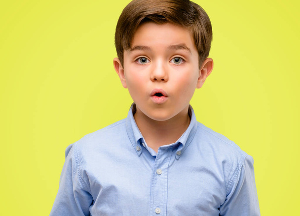 Όμορφος νήπιο παιδί με πράσινα μάτια, ευτυχισμένη και έκπληκτος επευφημίες εκφράζοντας wow κίνηση πάνω από το κίτρινο φόντο - Φωτογραφία, εικόνα