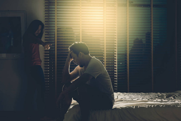 nyomott pár férj és a feleség ül a fej a kezét az ágyra, a sötét hálószobában a kevés fényben környezet, drámai koncepció - Fotó, kép