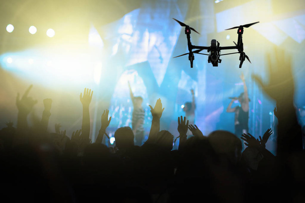 Closeup silueta Drone flying za video z koncertu davu a hudební fanklubu s Ukázat rukou akcí, která navázat písničkář v přední části jeviště, hudební a koncertní koncepce - Fotografie, Obrázek