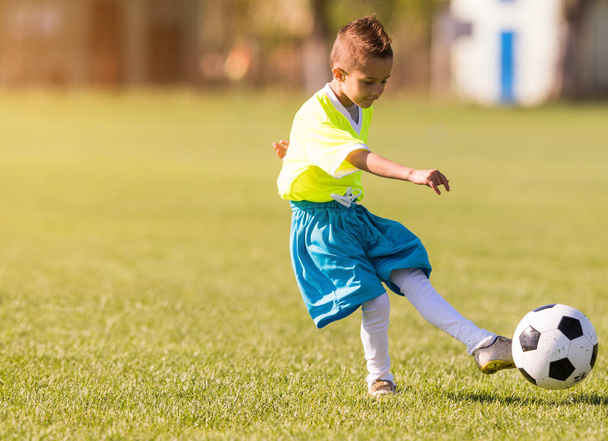 Boy kicking football on the sports field - Фото, изображение