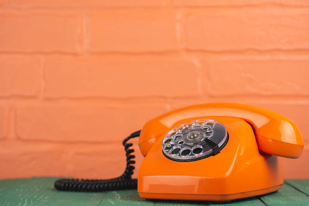 Old vintage orange phone on brick wall background - Photo, Image