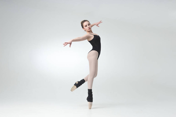 Ballerina in black outfit posing on toes, studio background. - 写真・画像