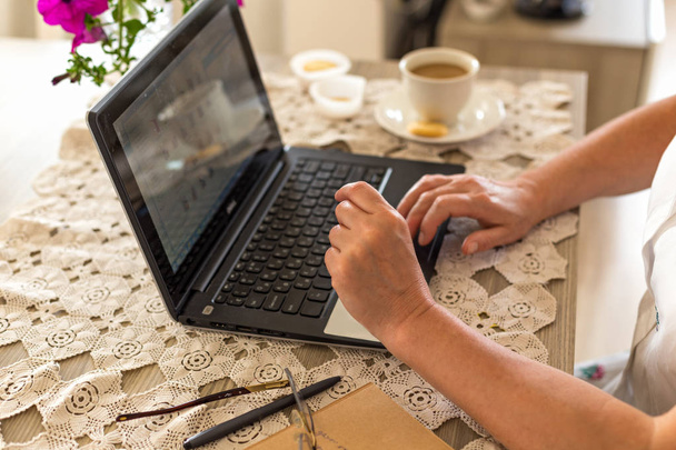 Весенний или летний фриланс и концепция домашнего офиса. Руки женщины, работающей на ноутбуке, помещены на кружевной стол
. - Фото, изображение