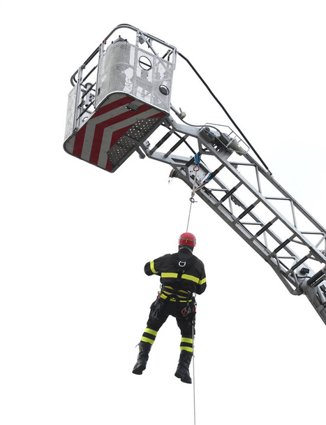 πυροσβέστης που αιωρούνταν στο κενό κατά τη διάρκεια μια άσκηση για το firehous - Φωτογραφία, εικόνα