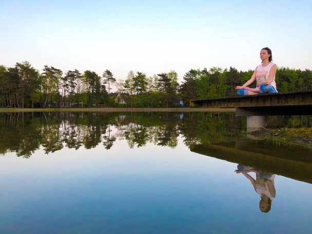 Mujer joven practica yoga y medita en la posición de loto
 - Foto, imagen