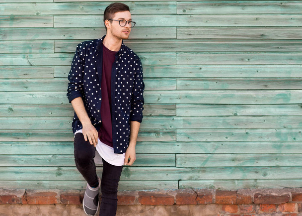 fashion guy hipster in fashion glasses posing on a wooden blue backgroun - Photo, image