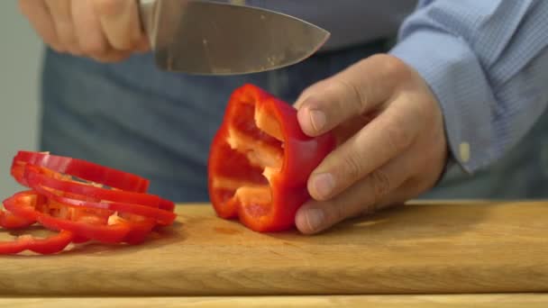 Closeup of hands of chef cook cutting red pepper on wooden table - Záběry, video