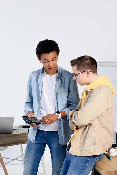 multicultural adolescente chicos mirando en el circuito informático en casa
 - Foto, imagen