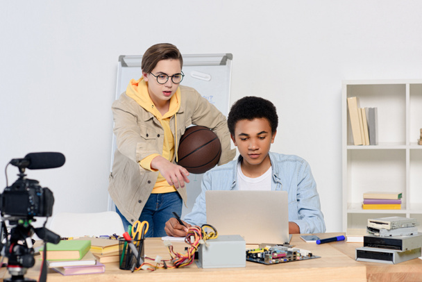 caucasian teenager pointing on something at laptop to african american friend at home - Photo, Image
