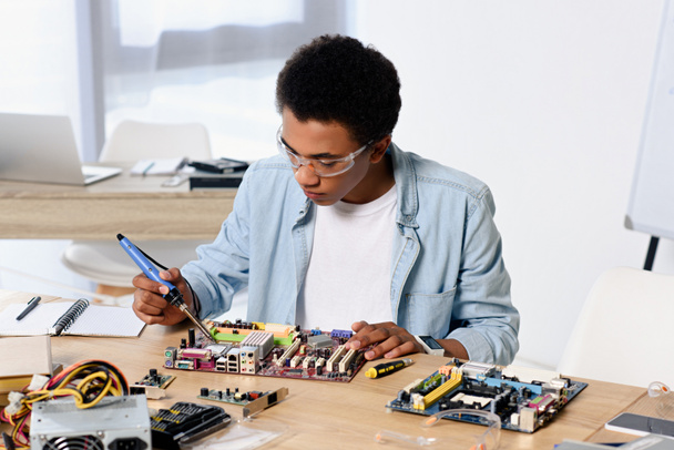 アフリカ系アメリカ人のティーンエイ ジャーがはんだ付けはんだごて自宅でコンピューター回路 - 写真・画像