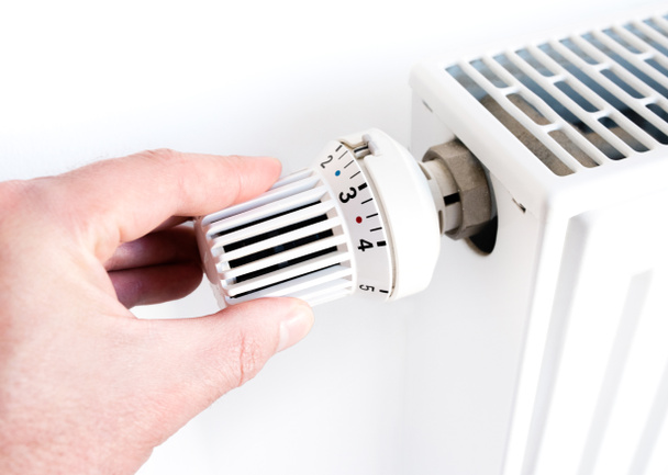 mies säätää lämpötilaa lämpöpatterin termostaatilla
 - Valokuva, kuva
