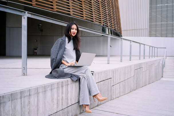 Beautiful stylish asian woman using laptop outdoors - Photo, image