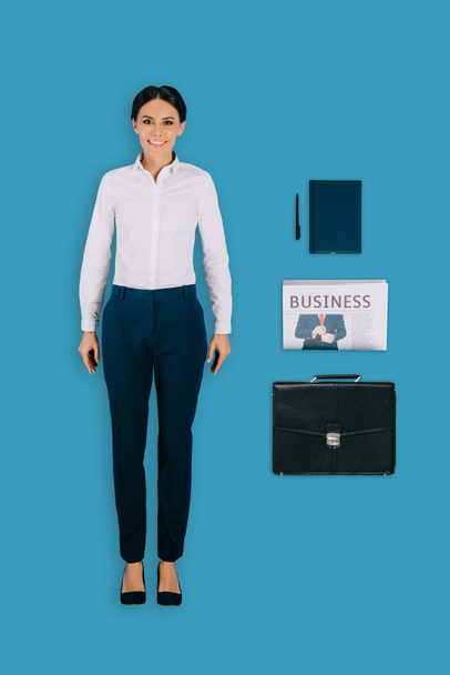 Draufsicht der Geschäftsfrau mit Aktentasche, Lehrbuch, Stift und Zeitung isoliert auf blauem Hintergrund - Foto, Bild
