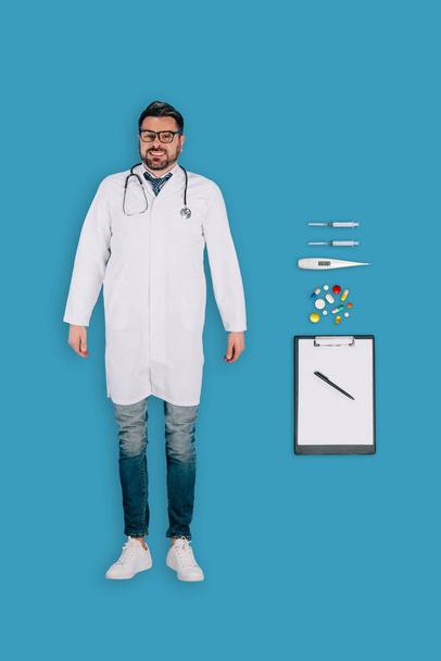 vista superior del médico masculino con estetoscopio, pastillas, portapapeles, jeringas, termómetro aislado sobre fondo azul
 - Foto, imagen