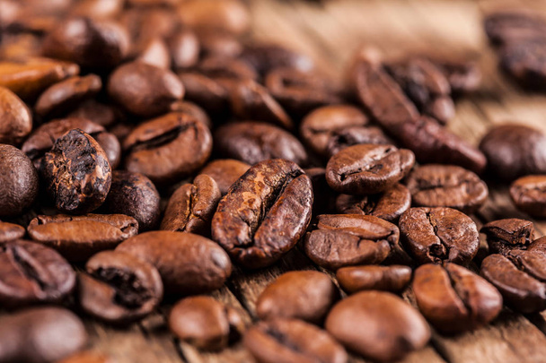 Жареный кофе в зернах на деревянном фоне - Фото, изображение