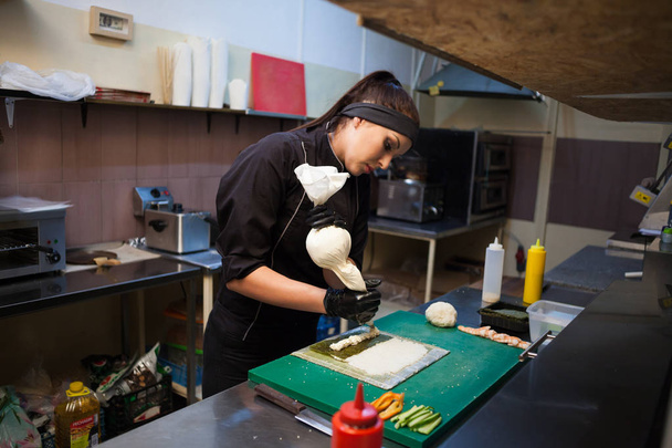 mulher em chef preto prepara restaurante de sushi
 - Foto, Imagem