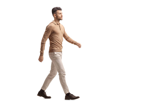 Full length profile shot of a young man walking isolated on white background - Fotó, kép