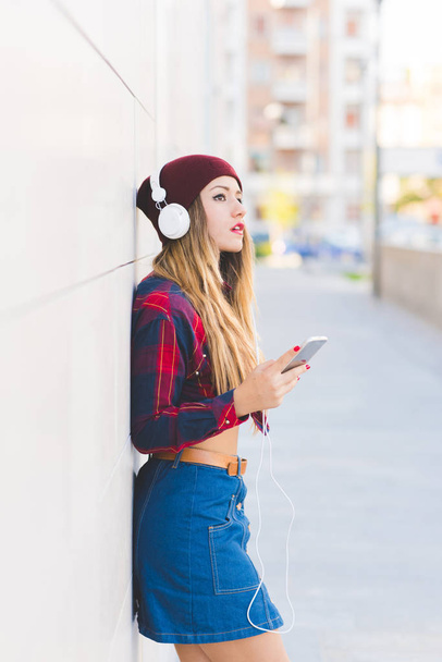 nuori nainen kuuntelee musiikkia älypuhelimella kaupungissa
  - Valokuva, kuva