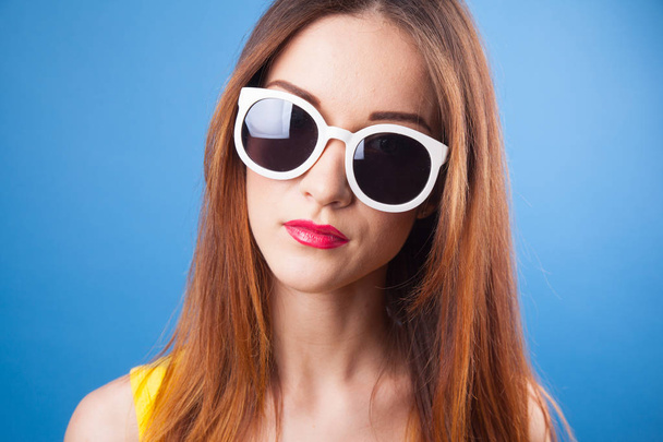 Beautiful young girl wear sunglasses on a blue background - Valokuva, kuva