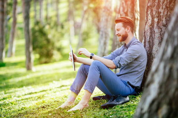 Handsome businessman using tablet pc in park - Photo, Image