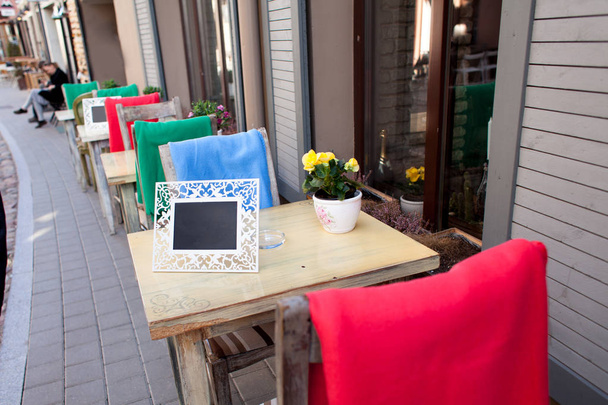 Szép és szép kis asztalok és székek kávézó egy sétálóutcában, egy üres tábla és asztal. - Fotó, kép