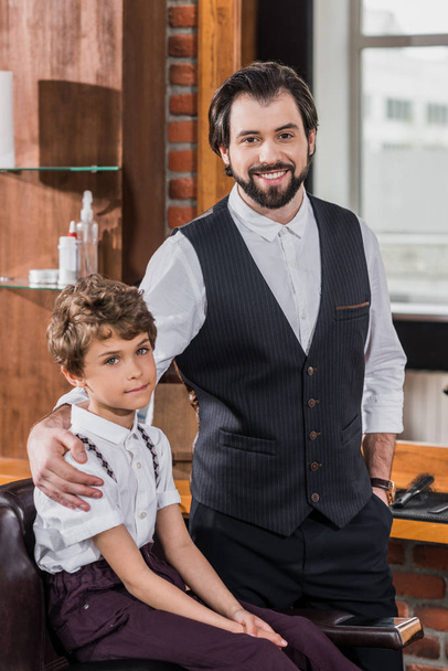 peluquero barbudo guapo con niño pequeño mirando a la cámara
 - Foto, Imagen