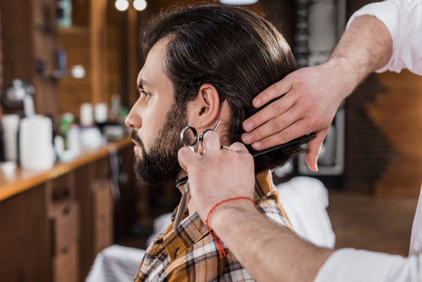 side view of handsome man getting haircut in barbershop - 写真・画像